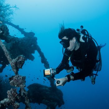 This picture shows a female diver and a shipwreck. The picture is featured by your Gili Meno dive center Divine Divers. Diving Gili Islands for beginners and experts. Fun Diving and courses and introduction dives. Accommodation and healthy restaurant on Gili Meno.